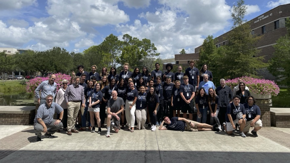 Group photo of campers and judges in front of the lake